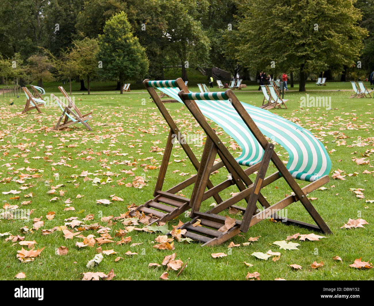Sedie a sdraio stabilire il vuoto in autunno gelido vento che soffia attraverso Hyde Park, Londra. Foto Stock