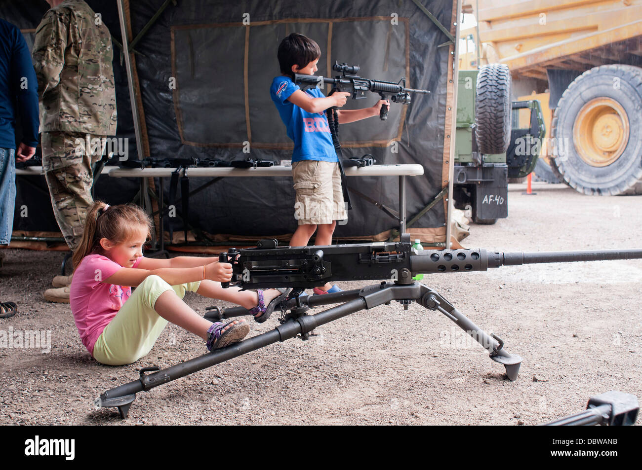 Una giovane ragazza si siede dietro una macchina pesante pistola come un ragazzo gioca con un fucile automatico durante una visualizzazione statica al Festival nautico Agosto 2, 2013 in città Rogers, Michigan. Foto Stock