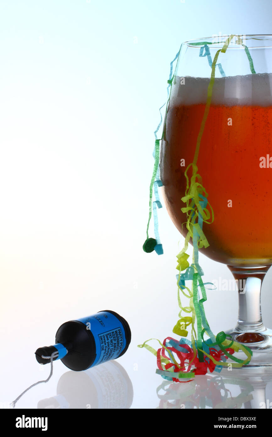 Bicchiere di birra con party popper e stelle filanti con spazio per la copia Foto Stock