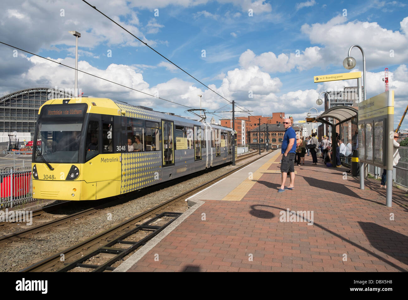 I passeggeri in attesa sulla piattaforma per tram Metrolink arrivando alla stazione Deansgate-Castlefield nel centro della città di Manchester Inghilterra England Regno Unito Foto Stock