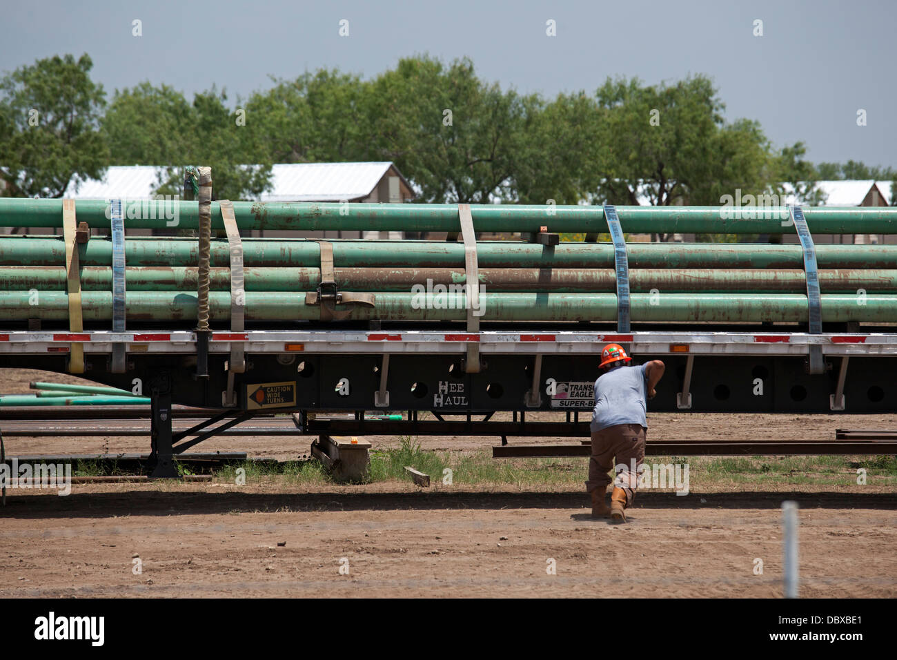 Un lavoratore assicura un carico di tubo sul suo carrello per uso nella Eagle Ford Shale, una zona di intensa produzione di petrolio e di gas. Foto Stock