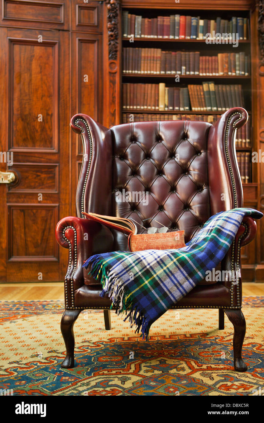 Tradizionale Chesterfield poltrona con tartan coperta in biblioteca classica camera Foto Stock