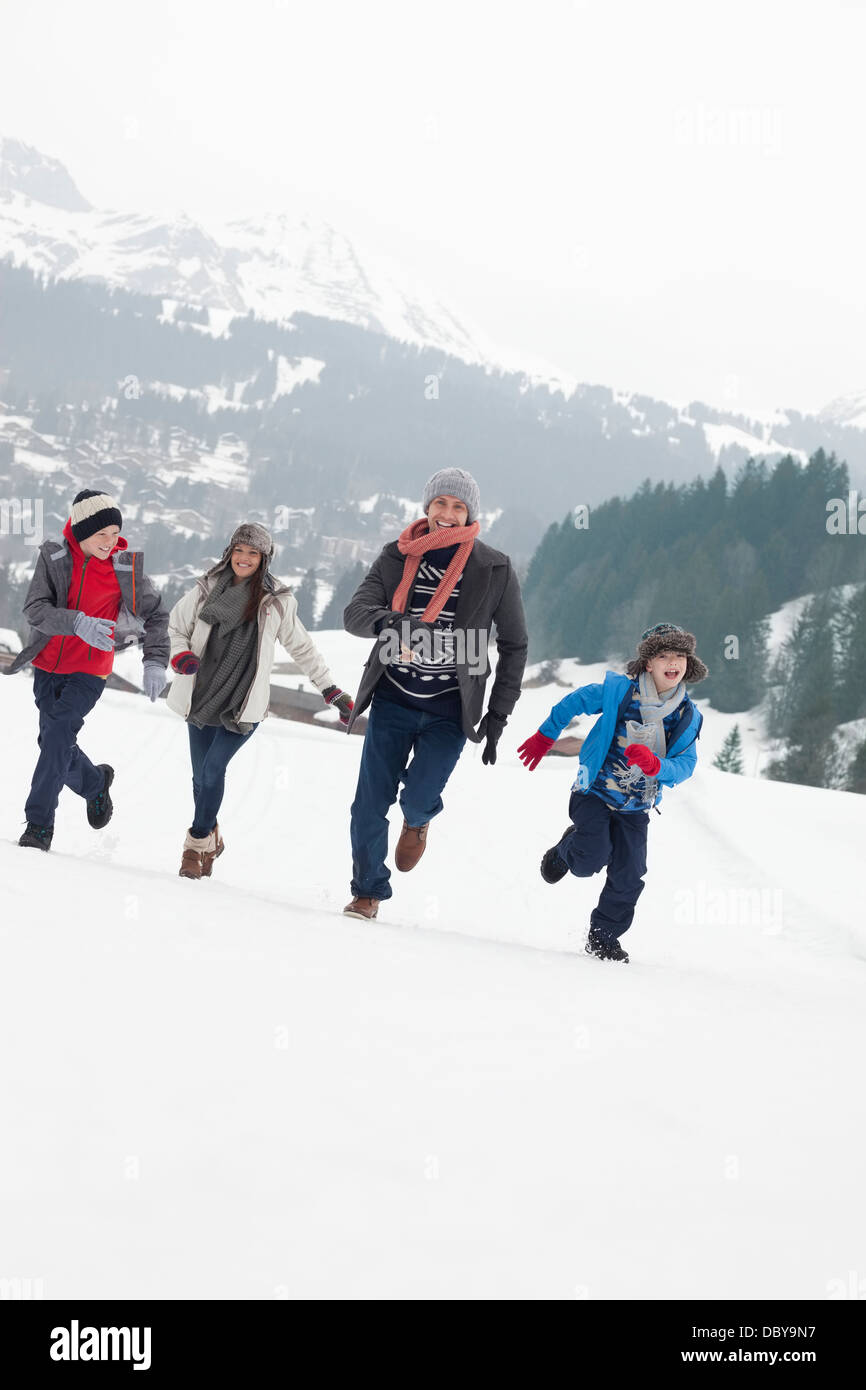 La famiglia felice in esecuzione in campo nevoso Foto Stock