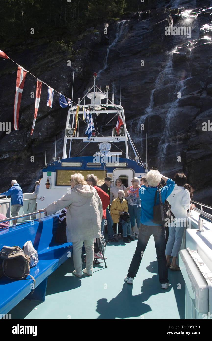 Modalen Norvegia Europa turisti su sun deck di fjord escursioni barca sotto le scogliere imponenti con cascata Foto Stock