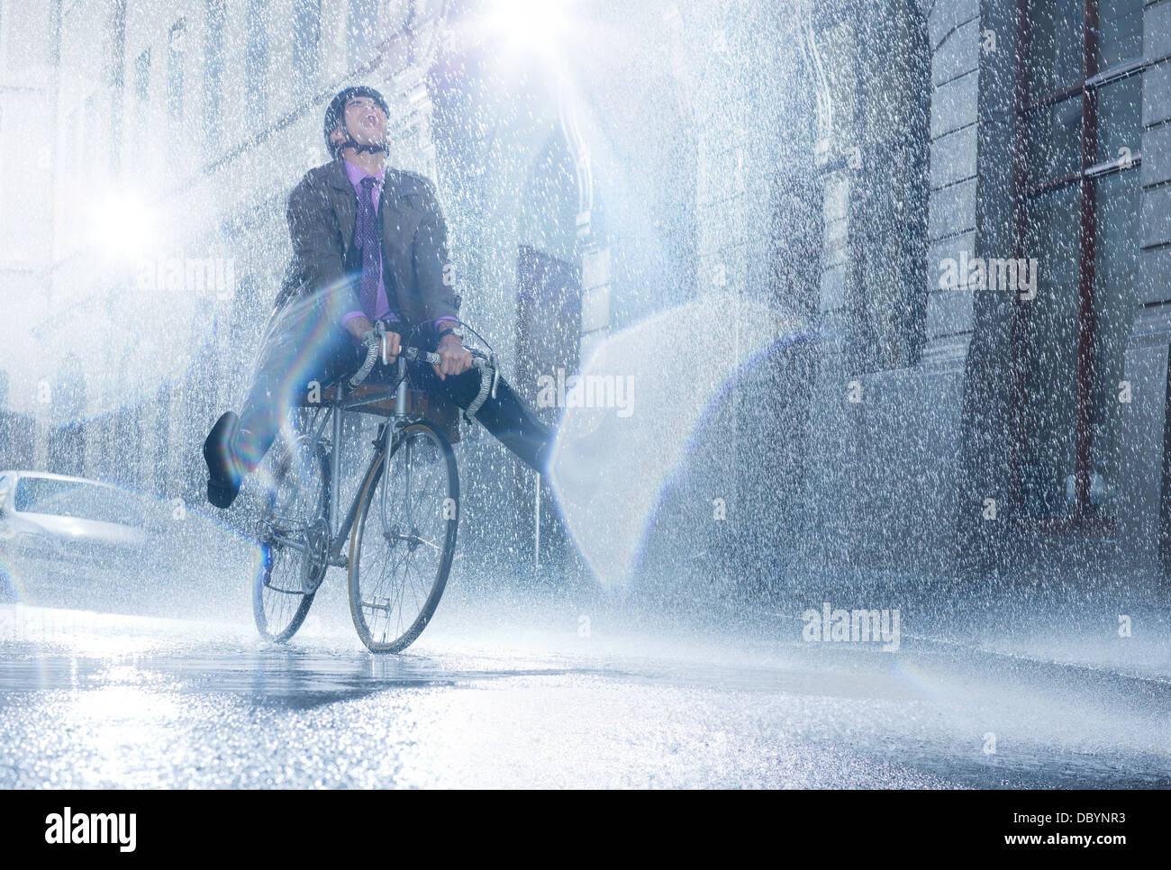 Imprenditore Bicicletta Equitazione in rainy street Foto Stock