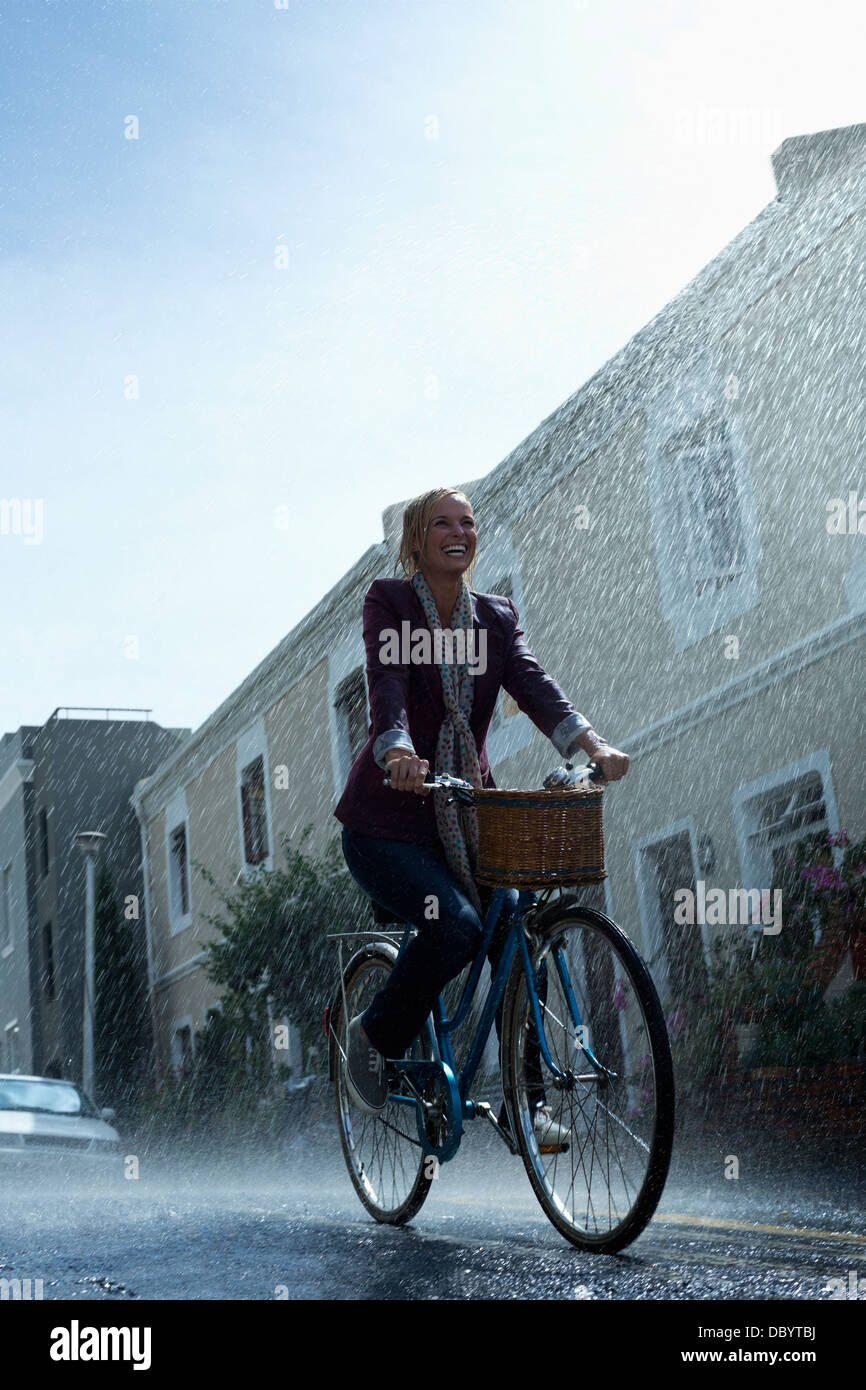 Donna felice equitazione Bicicletta in rainy street Foto Stock