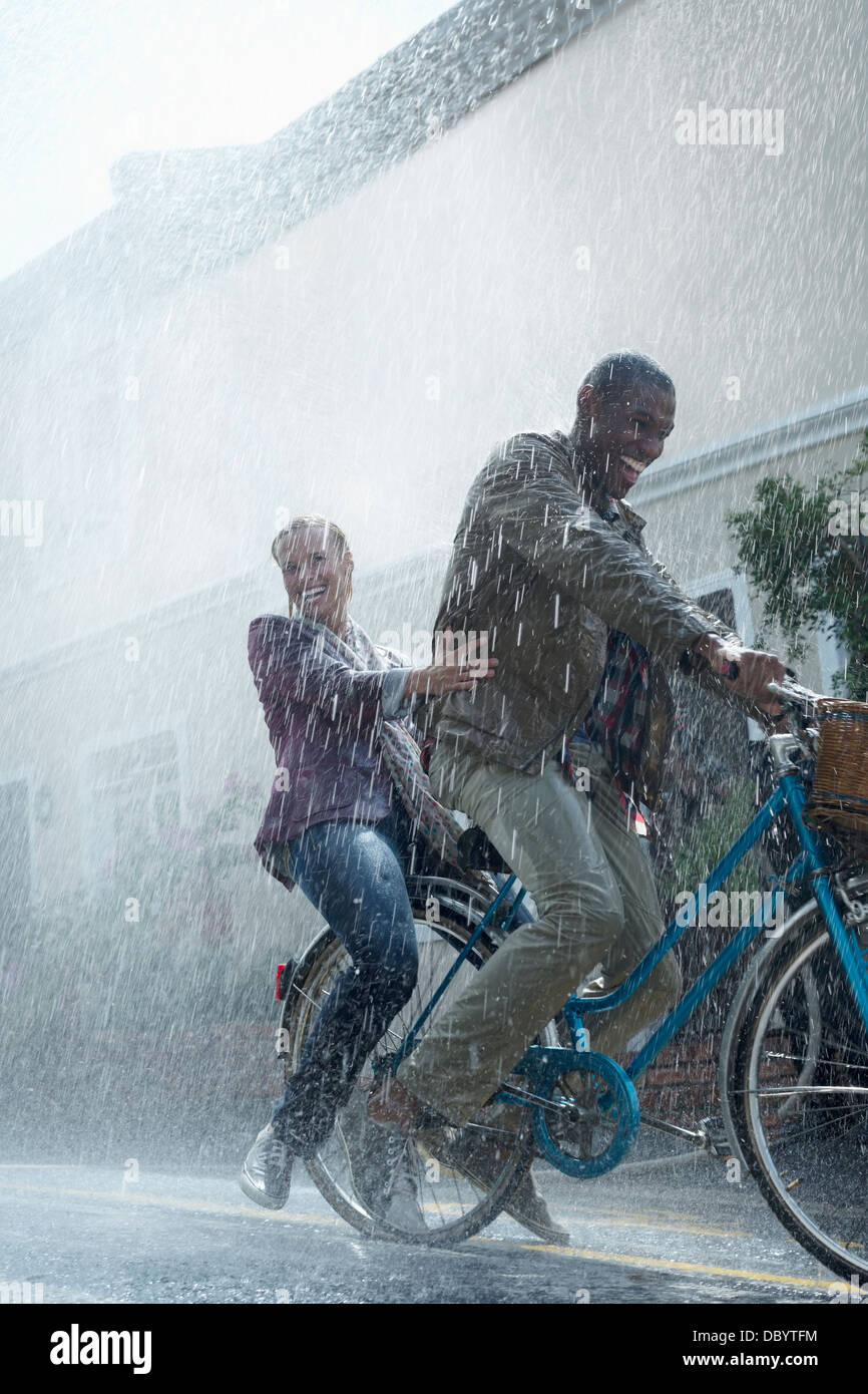 Coppia felice equitazione Bicicletta in rainy street Foto Stock