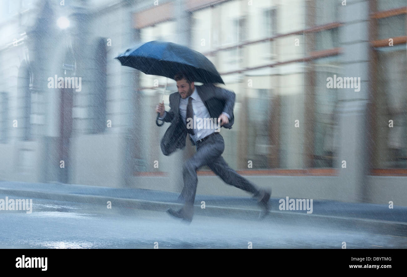 Imprenditore con ombrello in tutta rainy street Foto Stock
