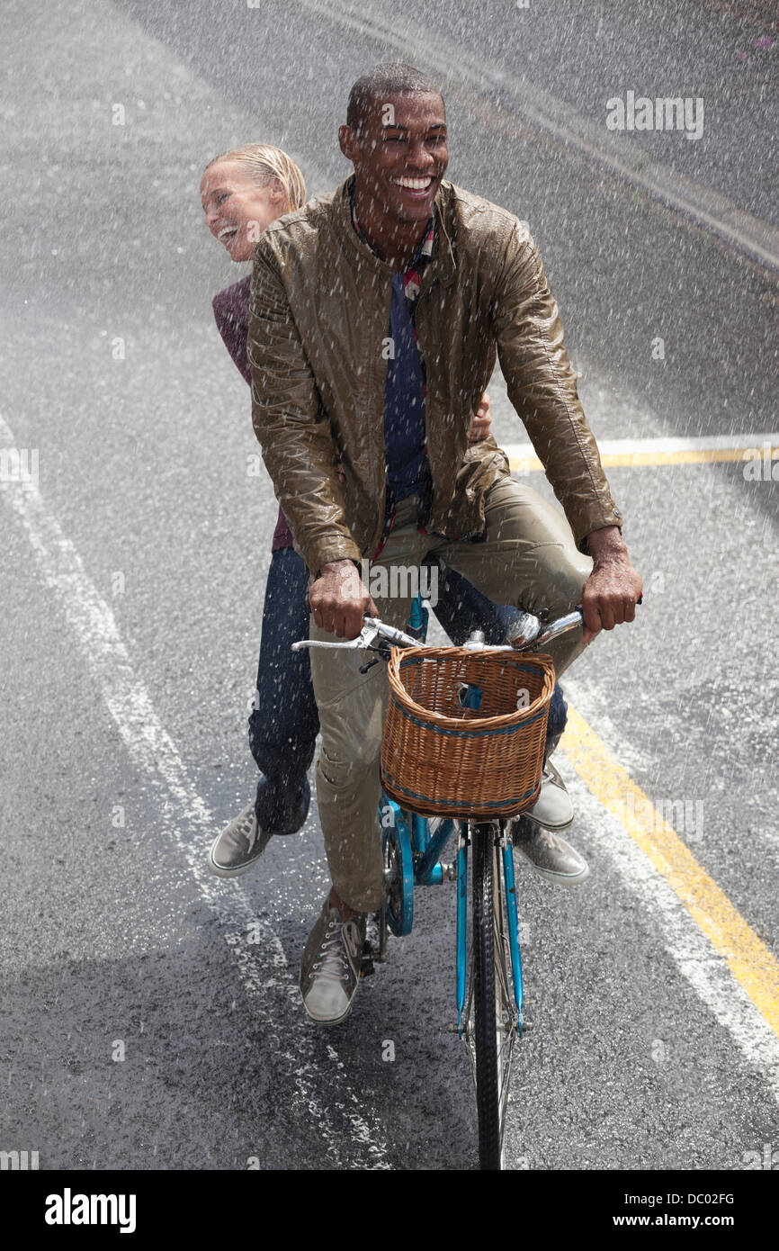Coppia felice equitazione Bicicletta in rainy street Foto Stock