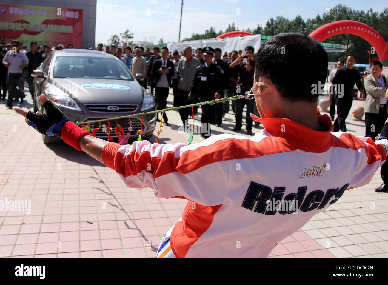 Nessun bisogno di chiamare la ripartizione di emergenza il servizio! Uno stunt performer da Shandong mostra che egli è in grado di trainare una macchina insieme con i suoi orecchi all'auto di seconda mano Piazza Affari nello Shandong, est della Cina di provincia. Cina - Settembre 2011 Foto Stock