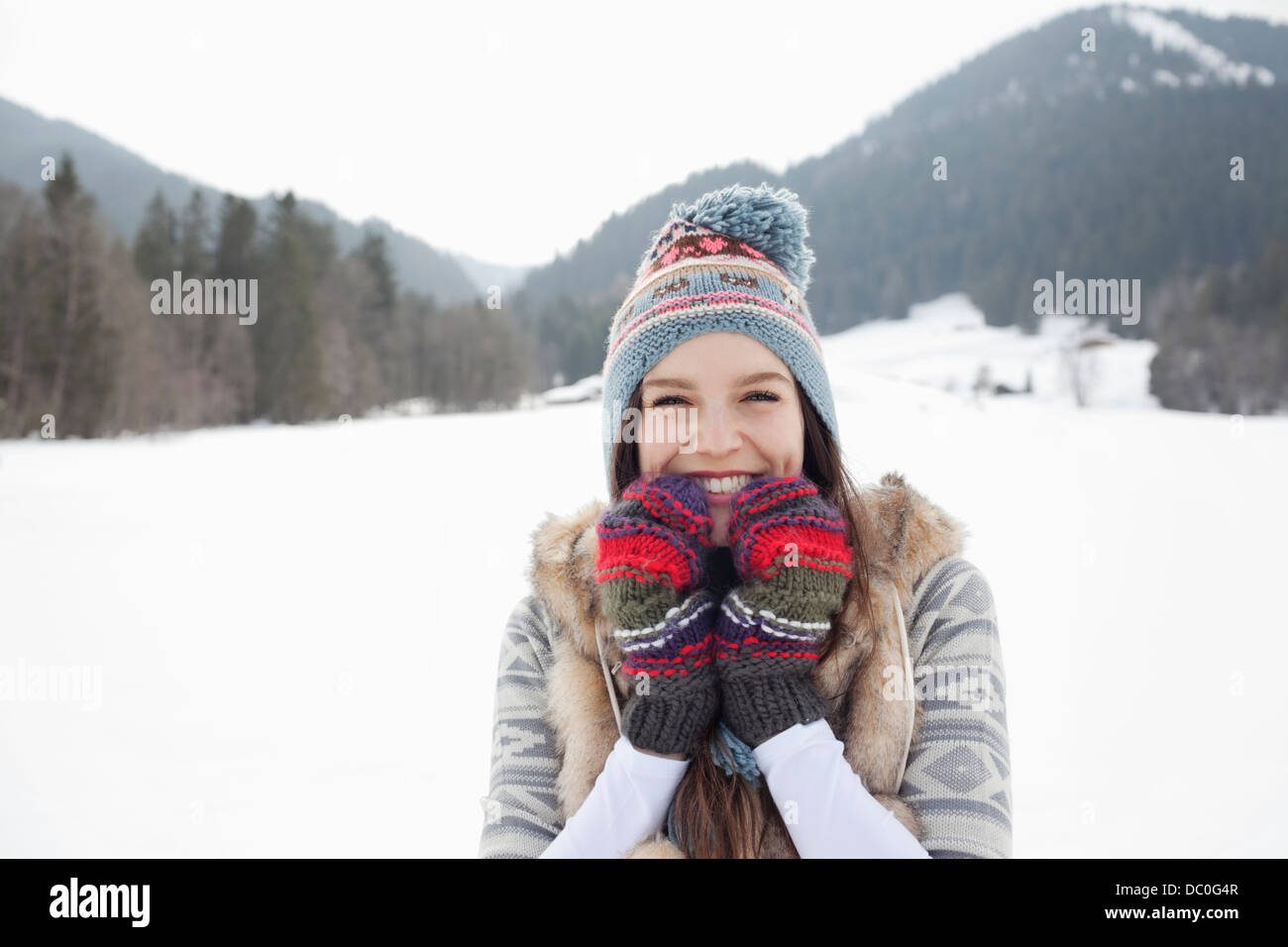 Ritratto di donna entusiasta di maglia da indossare guanti e cappello in campo nevoso Foto Stock