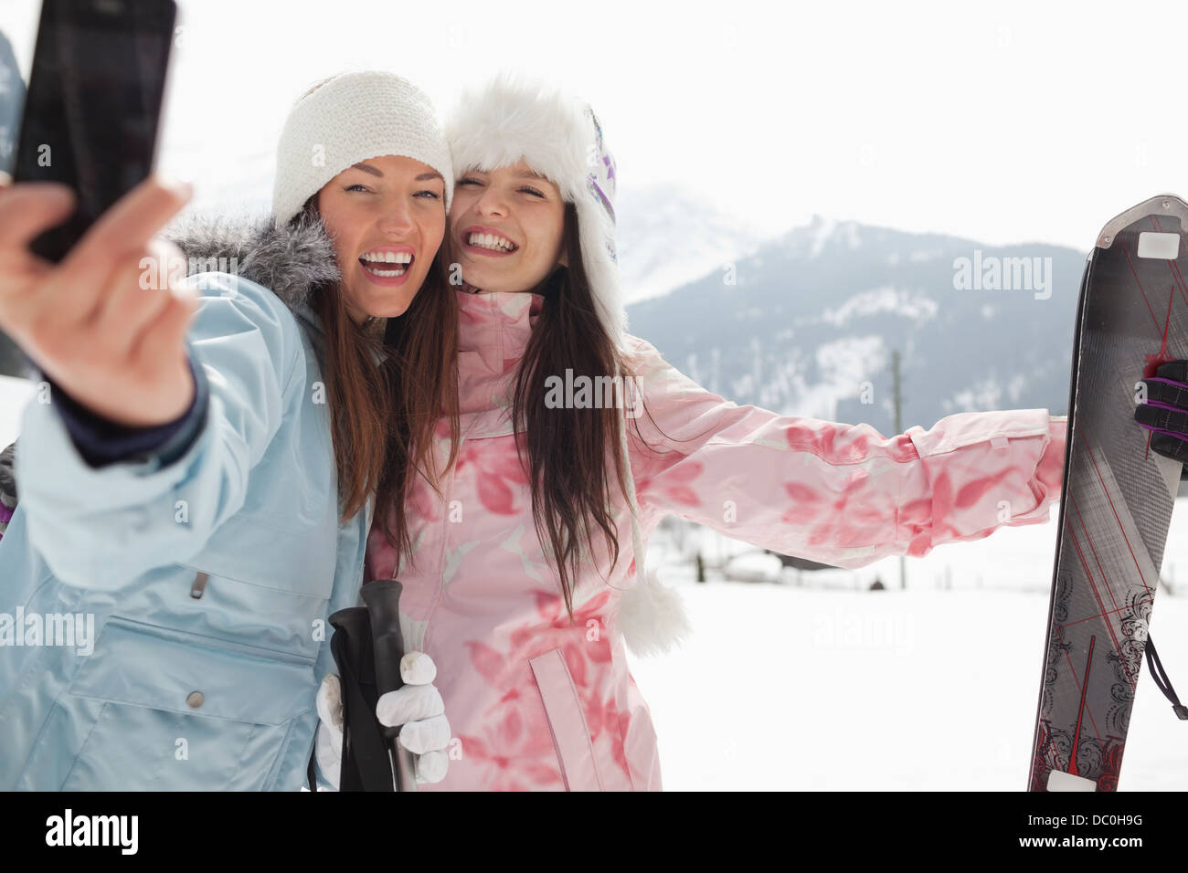 Donne entusiasta con sci tenendo autoritratto con la fotocamera del telefono nel campo Foto Stock