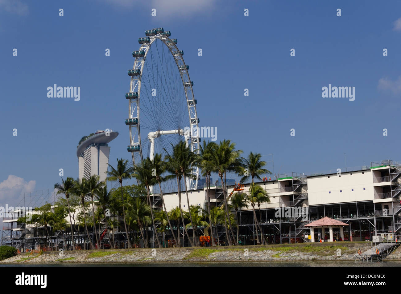 Preparazione della gara di Formula Uno con Singapore Flyer e Marina Bay Sands in background. In primo piano sono le palme, acqua Foto Stock