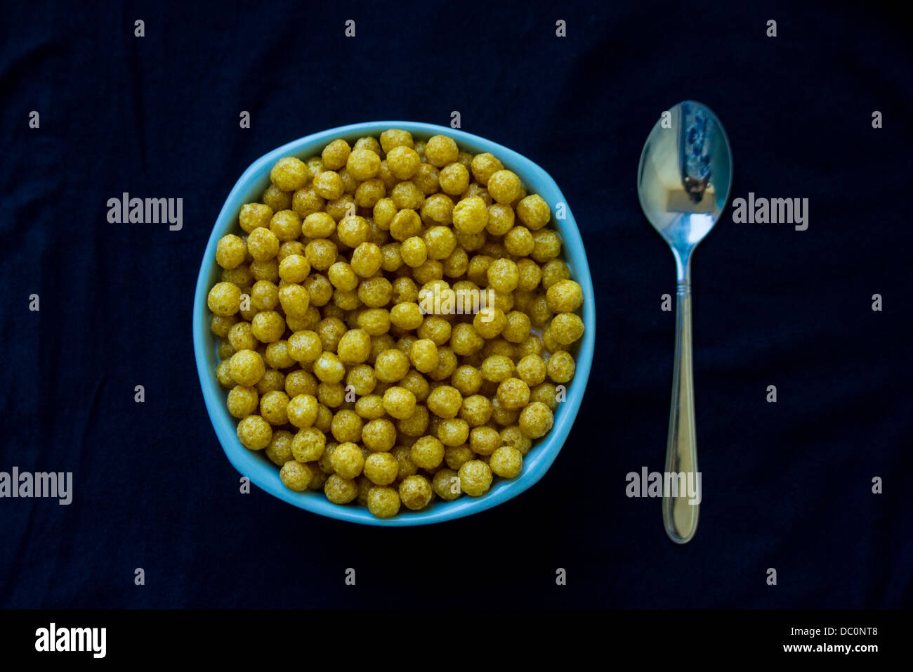 Vaso blu pieno con cereali e un cucchiaio Foto Stock