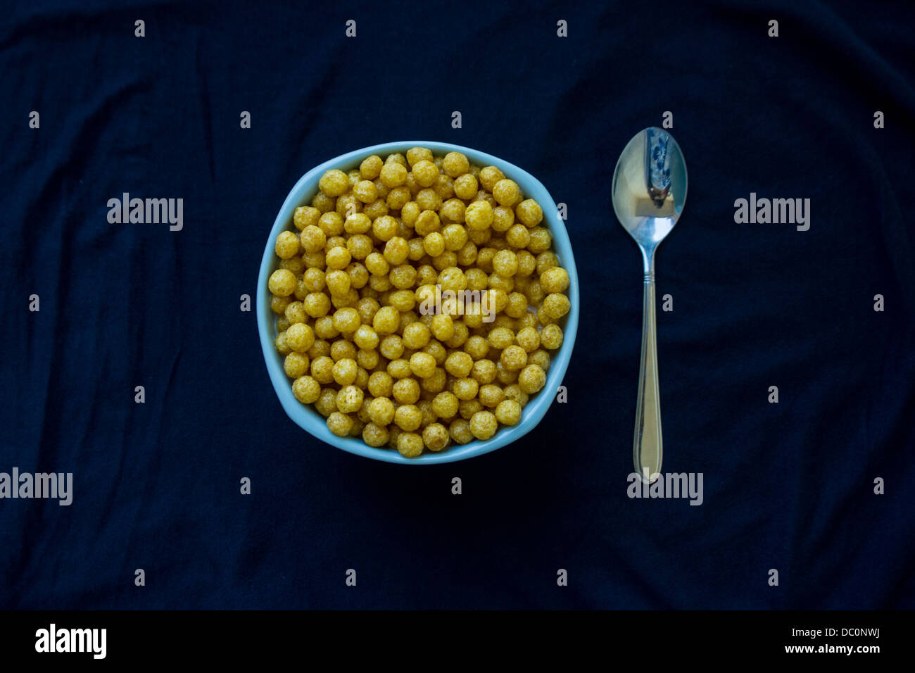 Vaso blu pieno con cereali e un cucchiaio Foto Stock