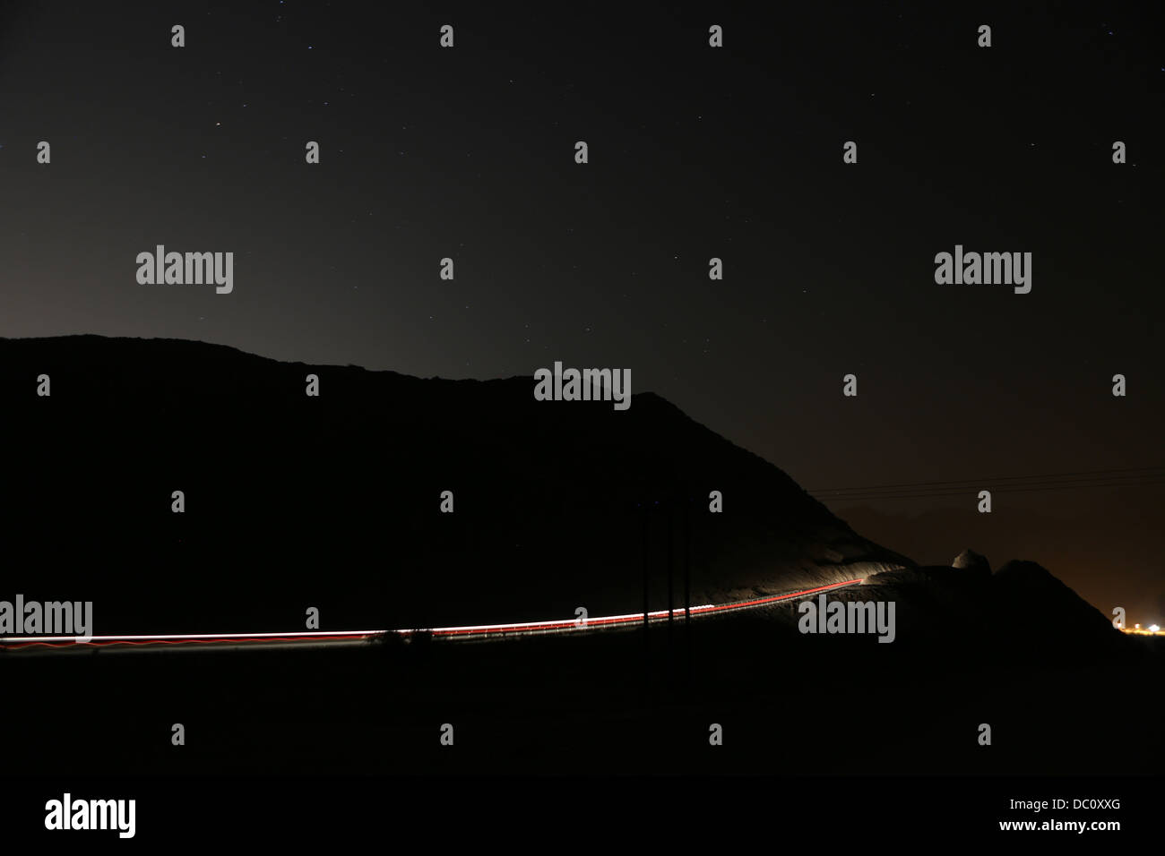 Sentieri di luce cattura fari auto passando attraverso le strade di montagna della penisola di Musandam, Oman Foto Stock