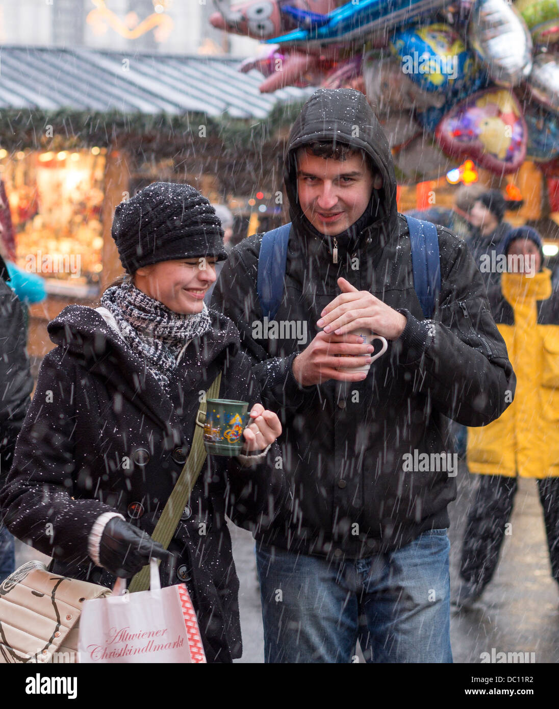 Nevicata improvvisa: proteggere il punzone. Un paio di godere di una improvvisa caduta di neve mentre lo shopping al Christkindlmarkt al Rathaus. Foto Stock