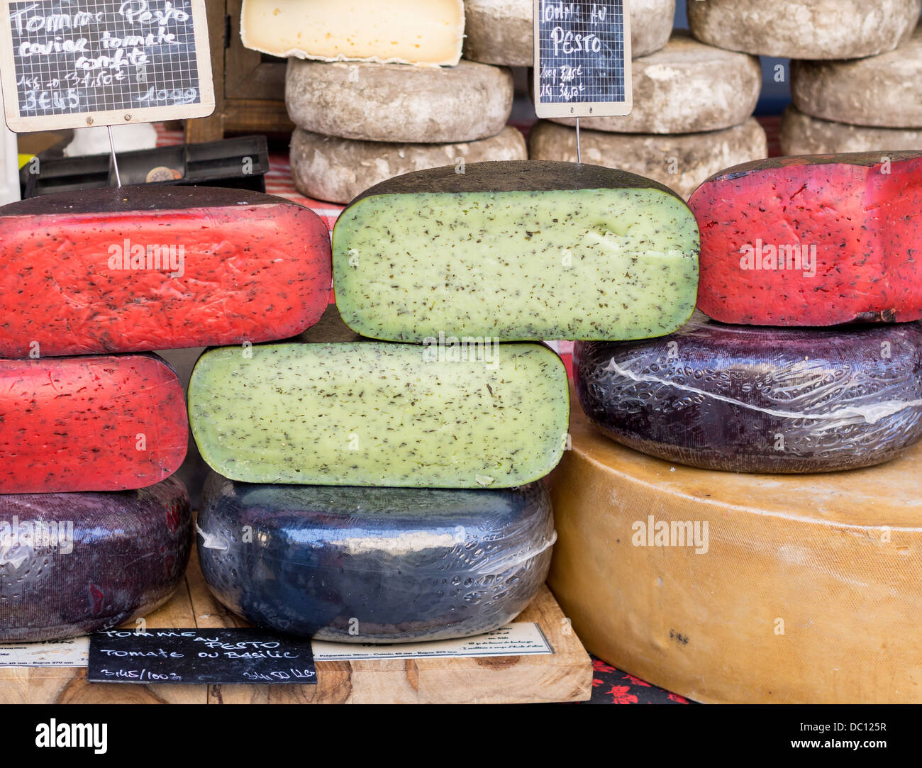 Formaggi colorati. Pesto e pomodoro prestano luminose i colori verde e rosso per formaggi aromatizzato sul display a un mercato in stallo. Foto Stock