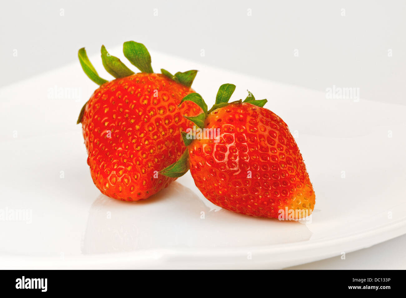 Due le bacche di fragola su una piastra bianca Foto Stock