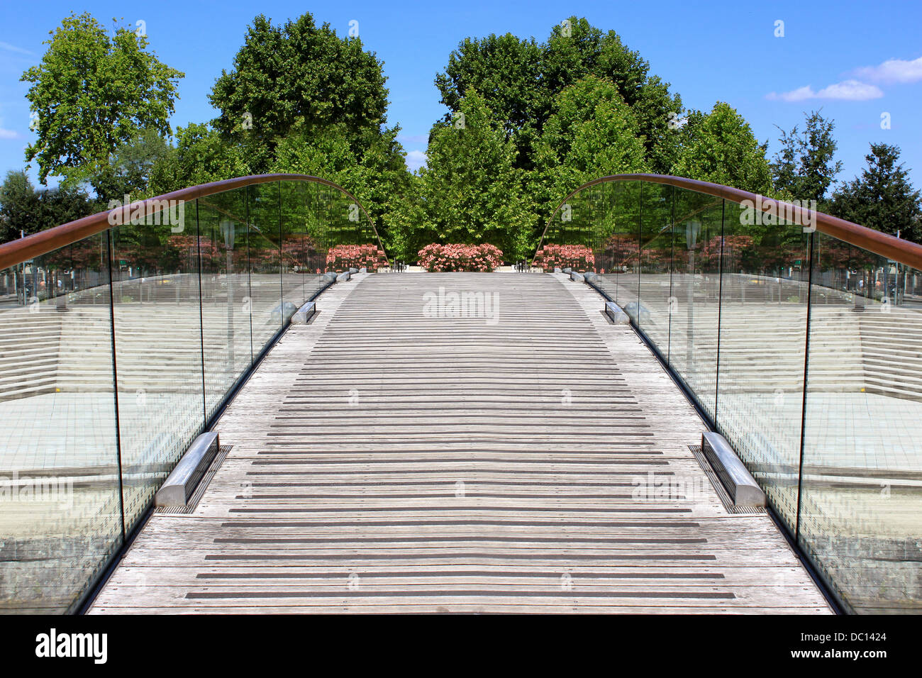 Un ponte pedonale su di un fiume in una città in fiore Foto Stock