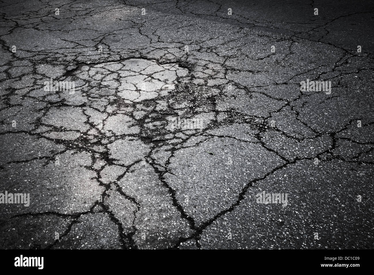 Dark strada asfaltata con crepe. Texture di sfondo Foto Stock
