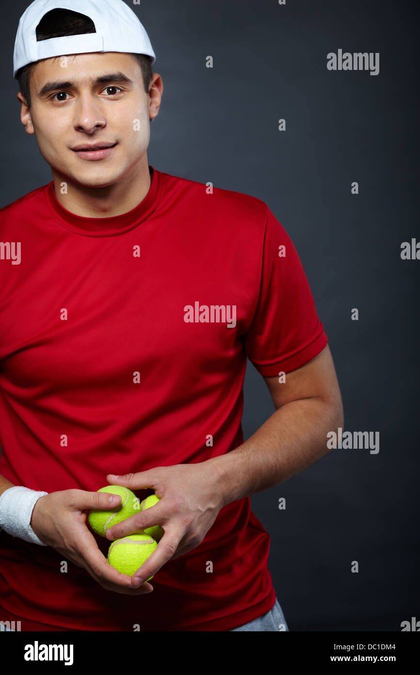 Ritratto di ragazzo sportivo tenendo le palle da tennis e guardando la fotocamera Foto Stock