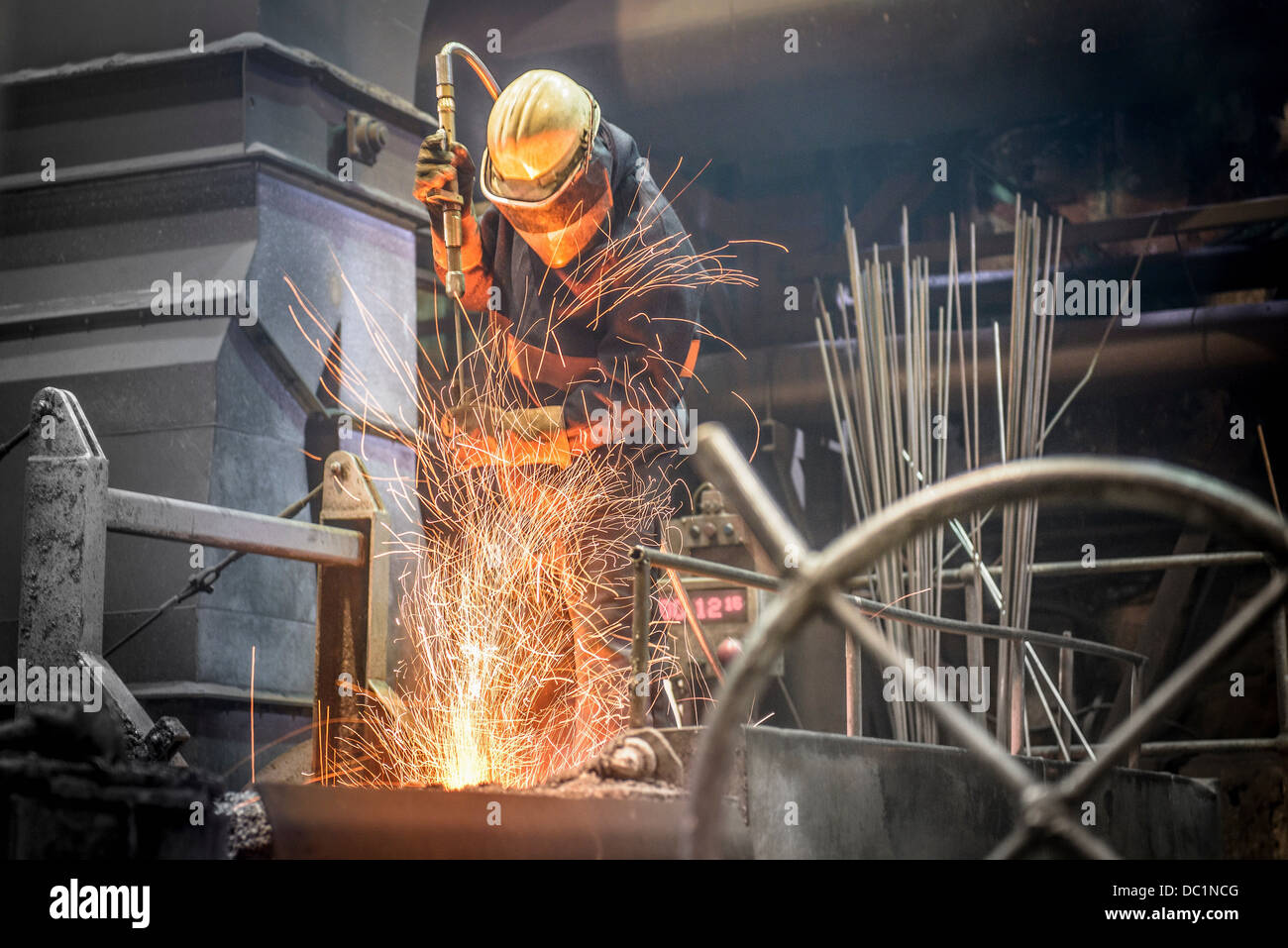Uomo in abbigliamento protettivo al lavoro nelle fonderie di acciaio Foto Stock