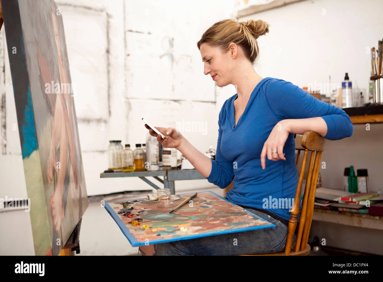 Metà donna adulta tramite telefono cellulare in artist's studio Foto Stock