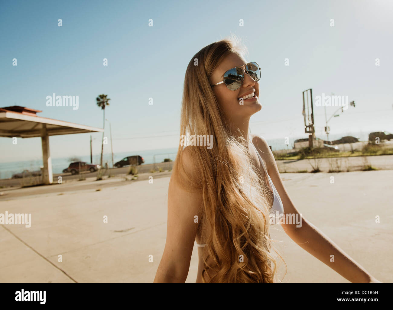 Giovane donna in bikini top e occhiali da sole, sorridente Foto Stock