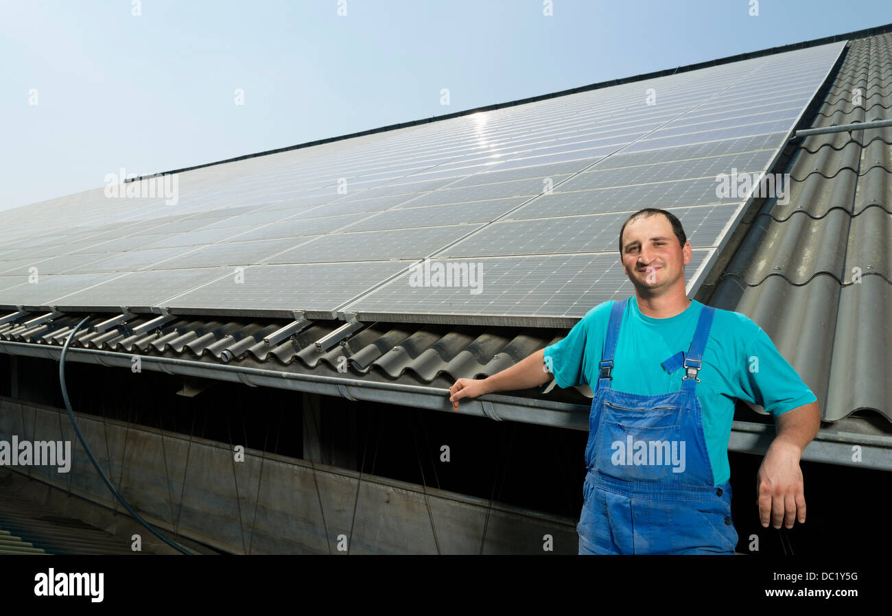 Ritratto di contadino con pannelli solari sul tetto del granaio, Waldfeucht-Bocket, Germania Foto Stock