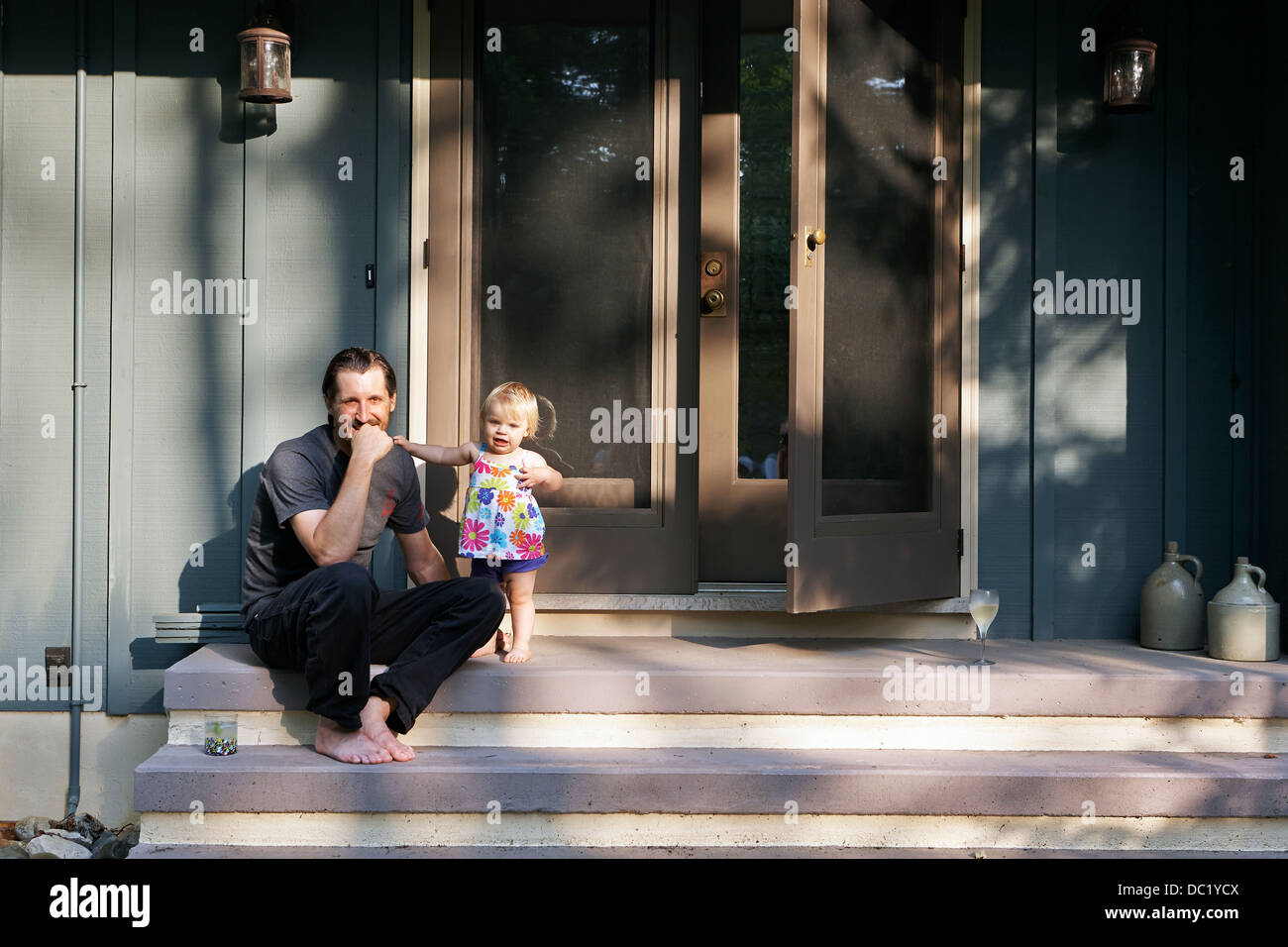 Coppia uomo seduto sui gradini con la giovane figlia, ritratto Foto Stock