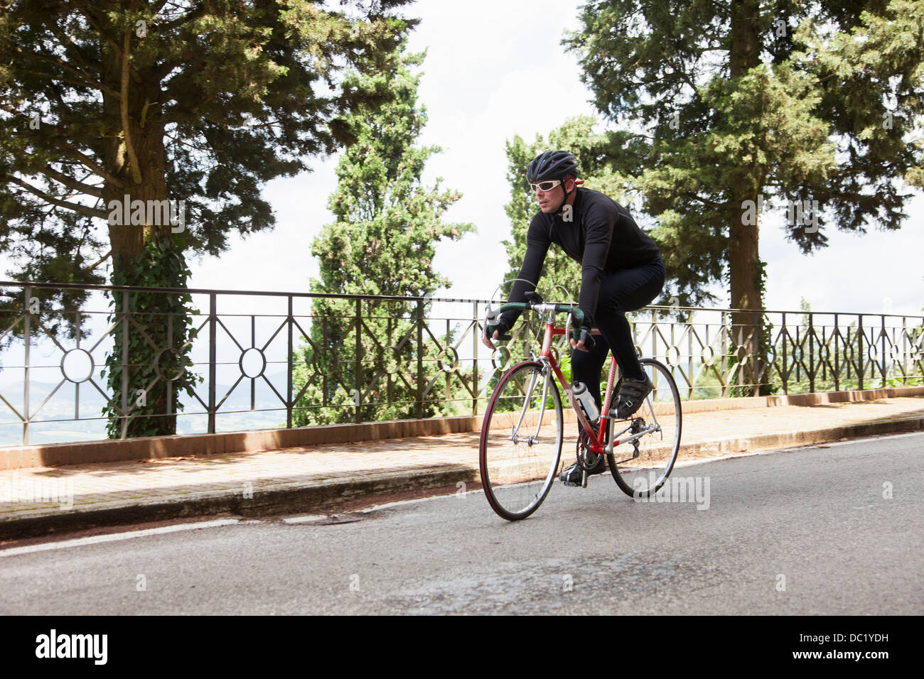 Ciclista riding down road in Umbria, Italia Foto Stock