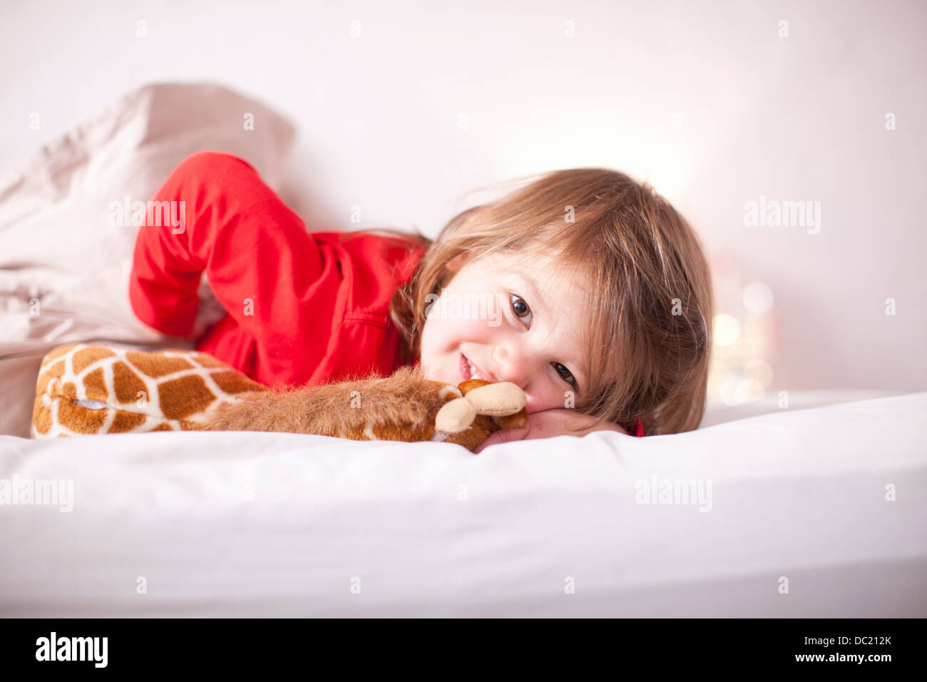 Ragazza giovane sdraiato sul letto con toy giraffa Foto Stock