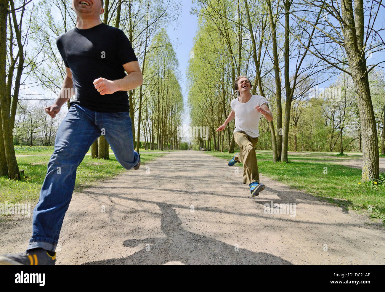 Metà uomini adulti racing ogni altro sul sentiero del parco Foto Stock