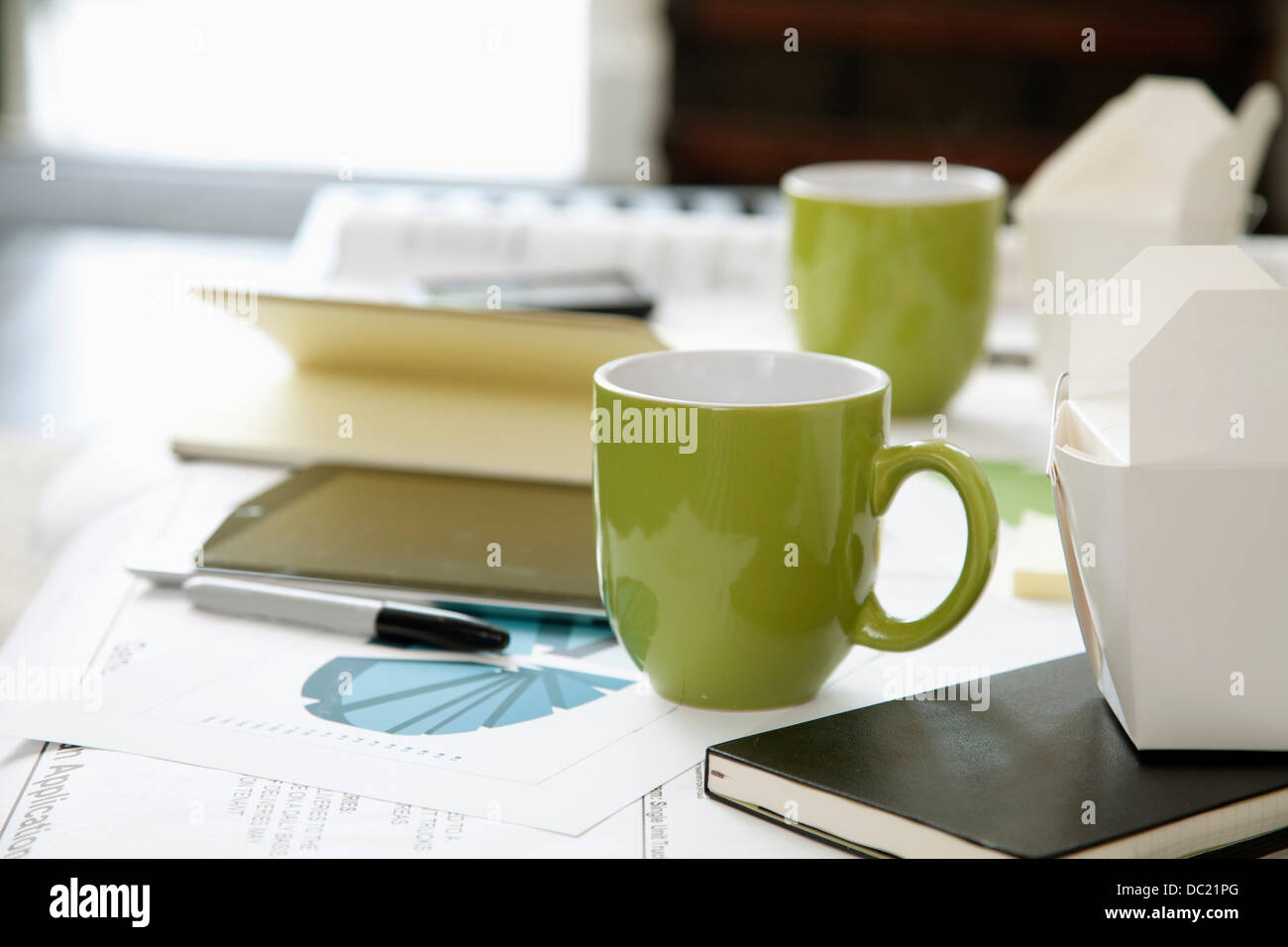 La documentazione di grafici, diagrammi e tazze sul tavolino da caffè Foto Stock
