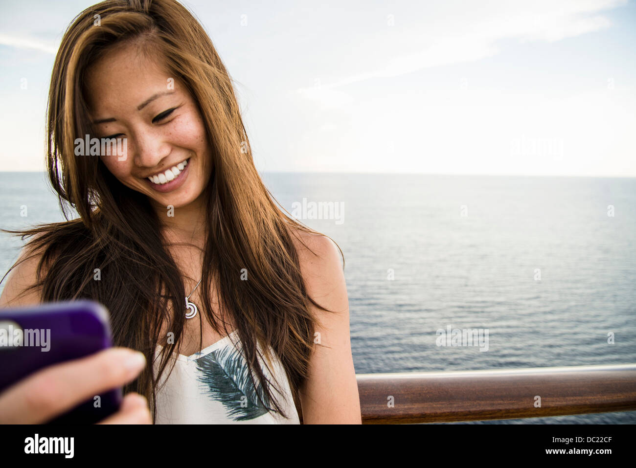 Giovane donna utilizzando il telefono cellulare in mare Foto Stock