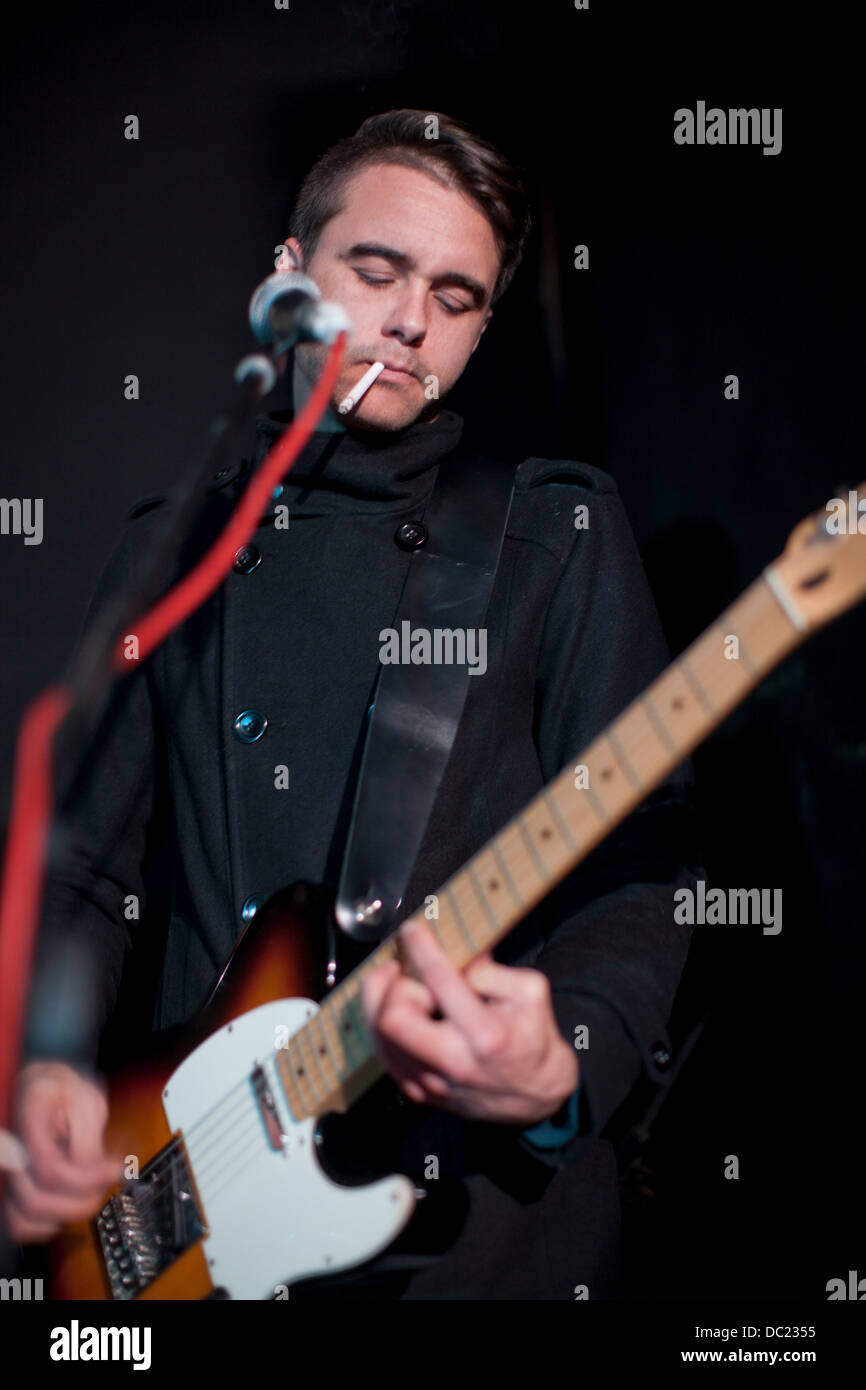 Uomo a suonare la chitarra sul palco in club Foto Stock