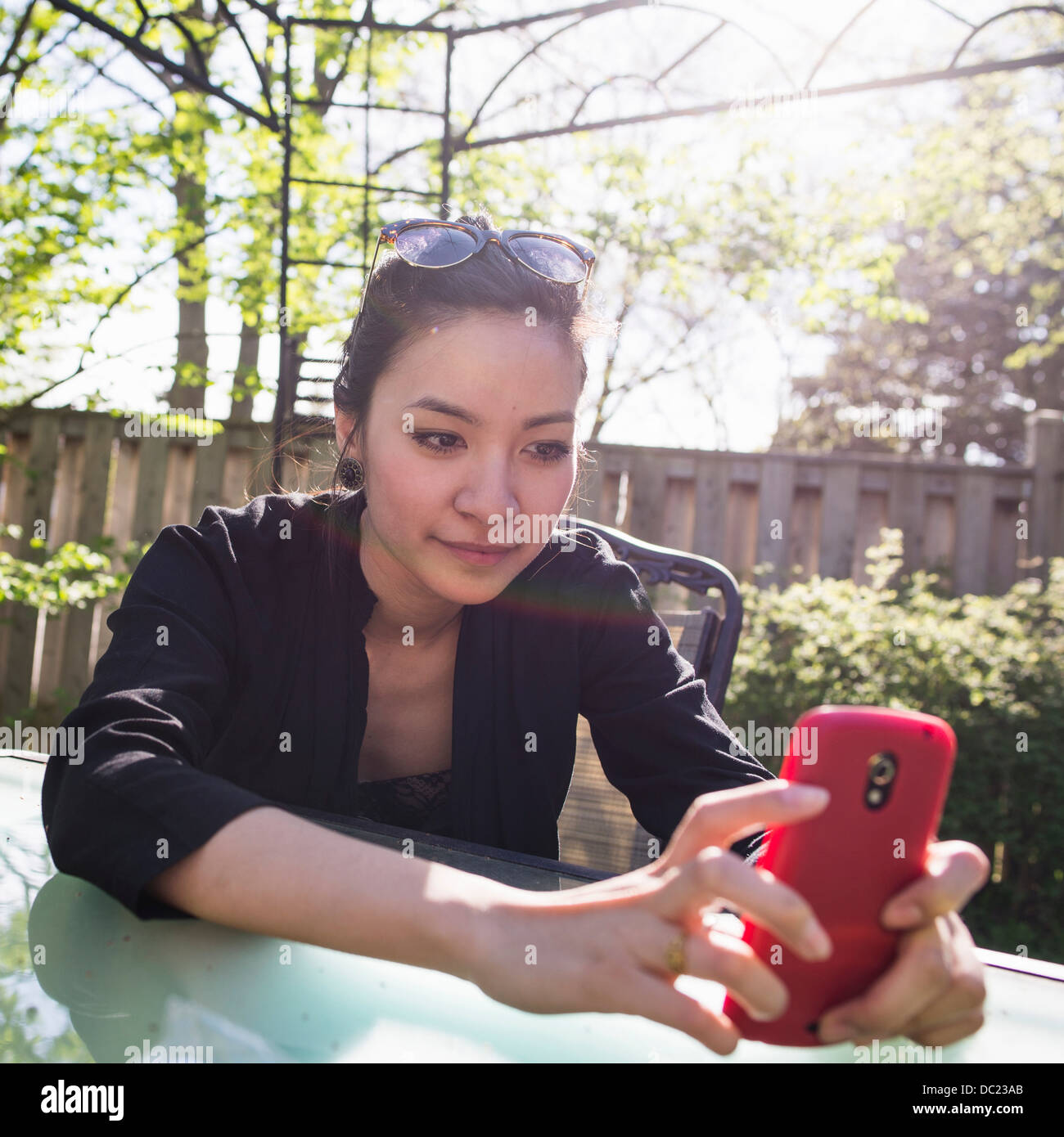 Giovane donna utilizzando il rosso telefono cellulare all'aperto Foto Stock