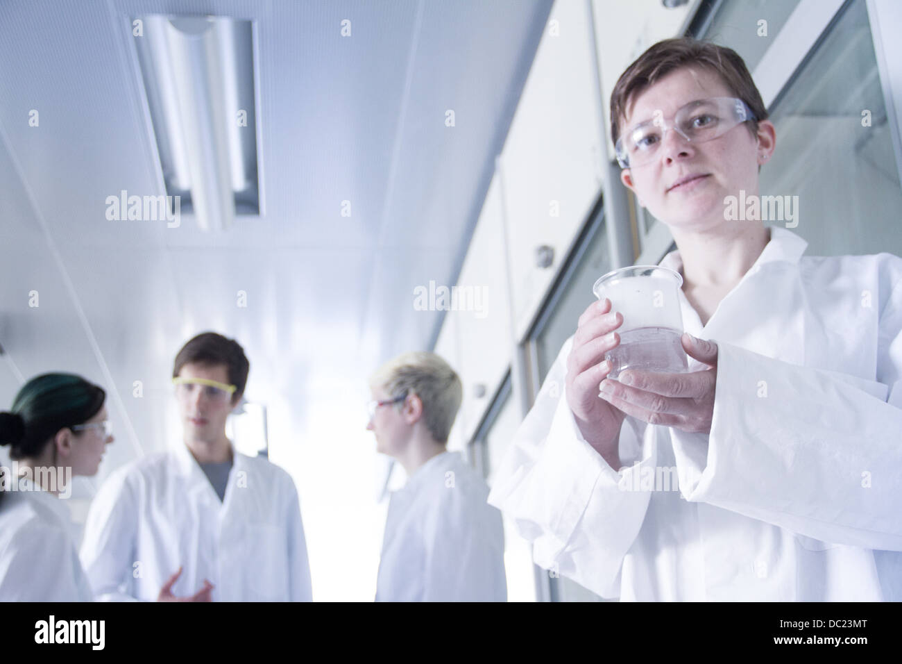 Studente di chimica bicchiere di contenimento in laboratorio, ritratto Foto Stock