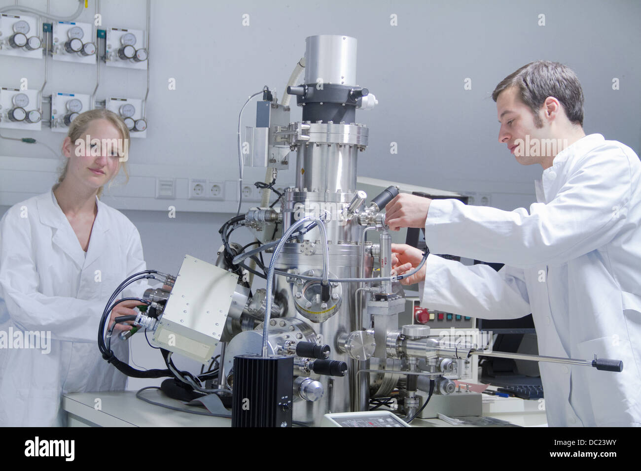 Due scienziati indossando camici da laboratorio utilizzando apparecchiature scientifiche Foto Stock