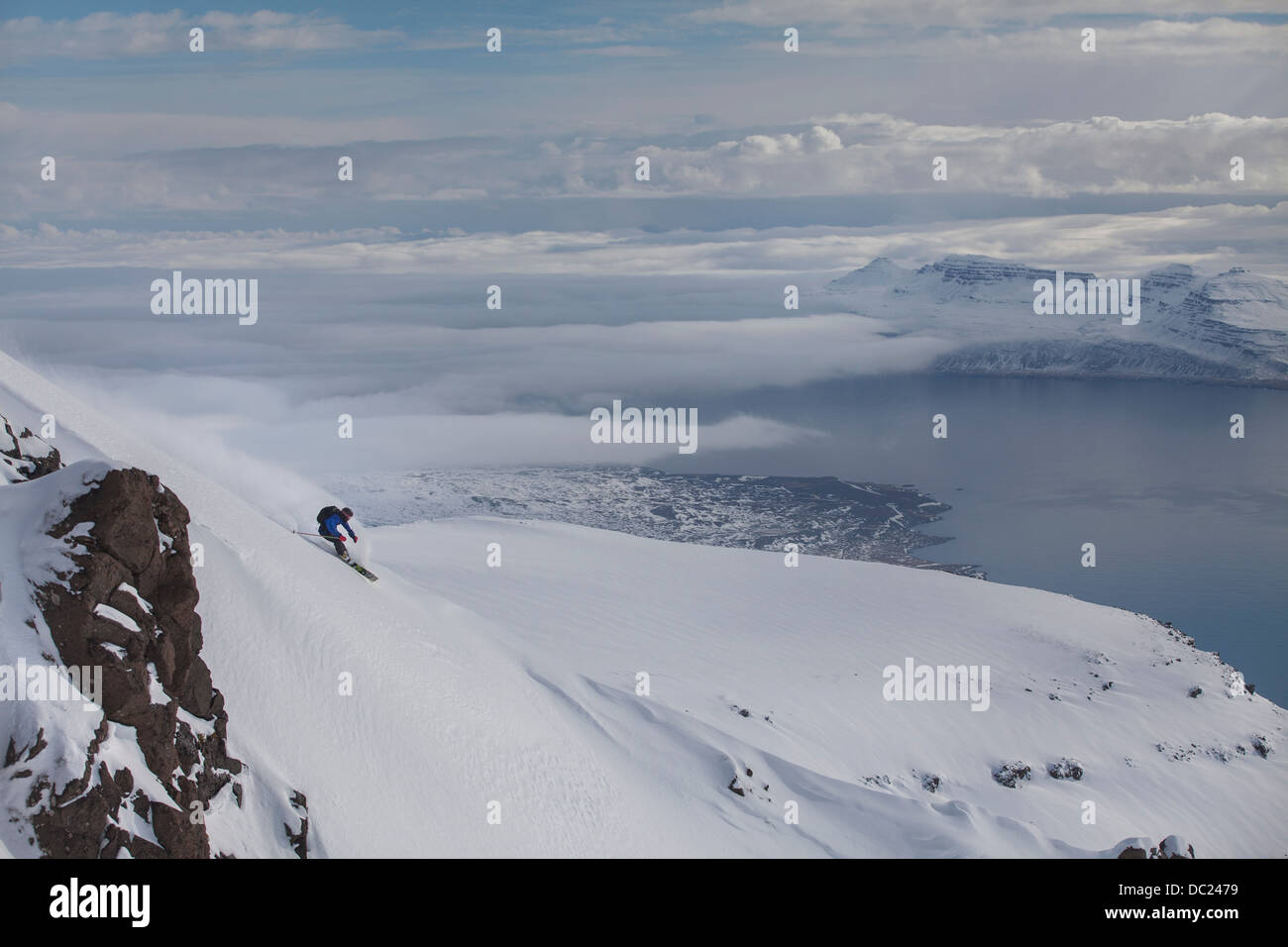 L uomo lo Snowboard giù in montagna Eskifjordur, Islanda Foto Stock