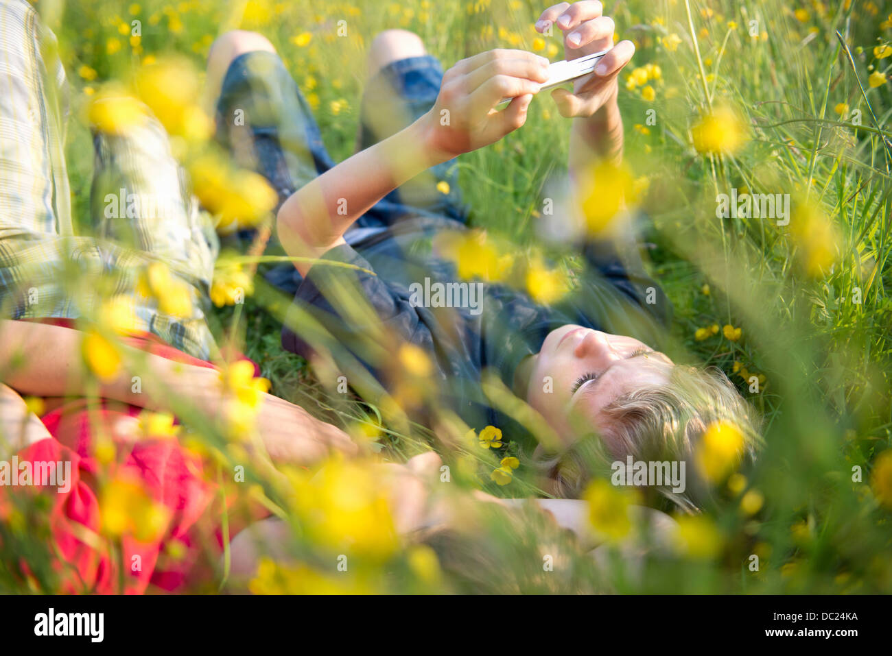 Ragazzi giacente in erba lunga la riproduzione sullo smartphone Foto Stock