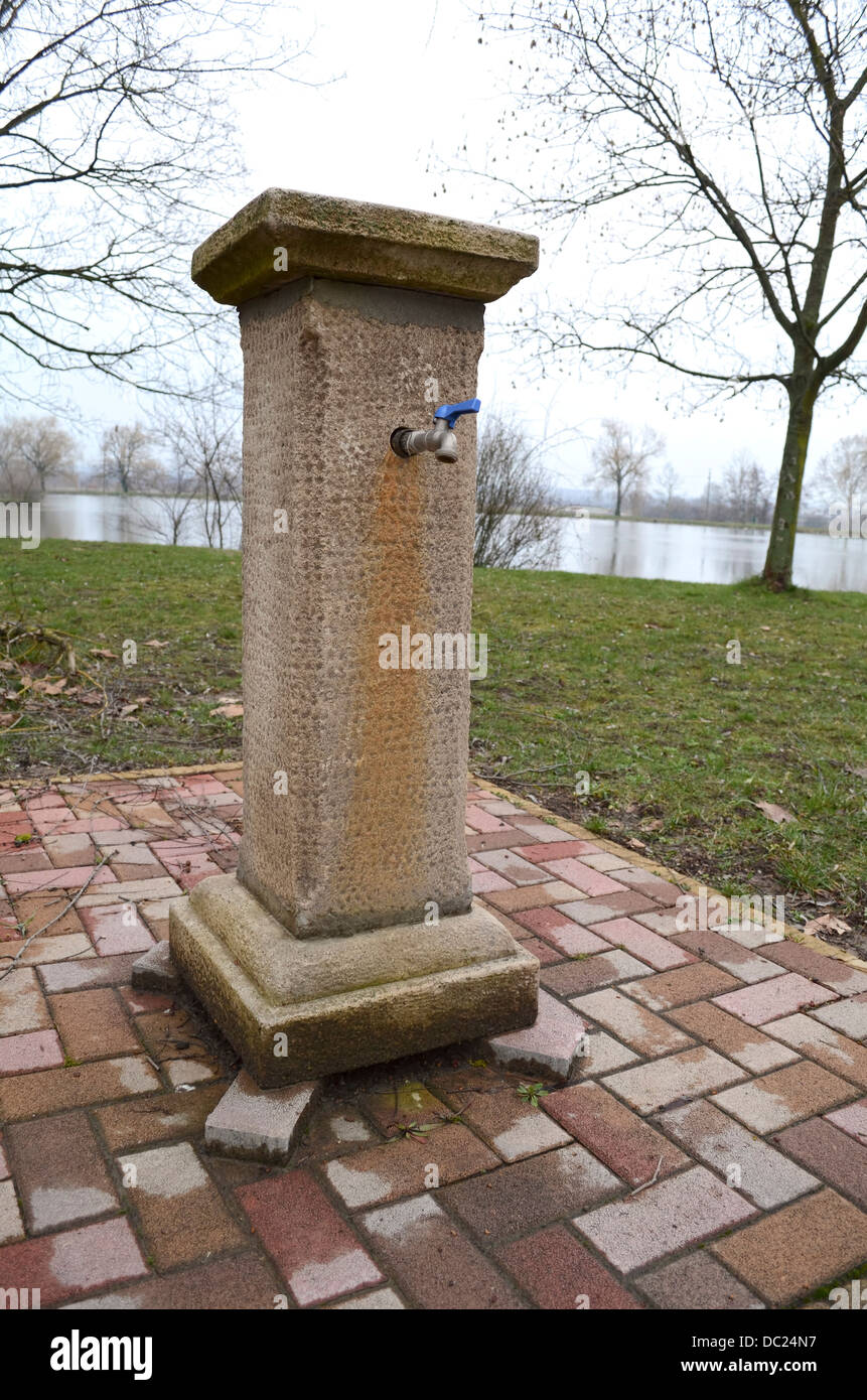 Marrone Anticato pozzo in pietra con rubinetto Foto Stock