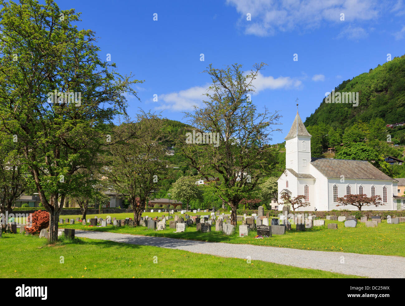 Bianco a doghe in legno chiesa e cimitero di borgo costiero su Hardangerfjorden. Øystese, Kvam, Hardanger, Hordaland, Norvegia Foto Stock