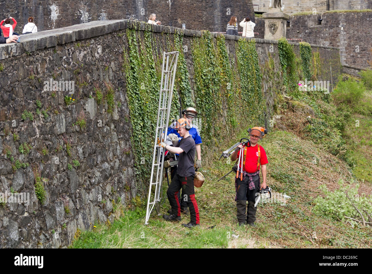 Personale con le scale per la manutenzione della parete e liane presso il Castello di Stirling. Al di sopra di esse, turisti diretti verso il castello Foto Stock