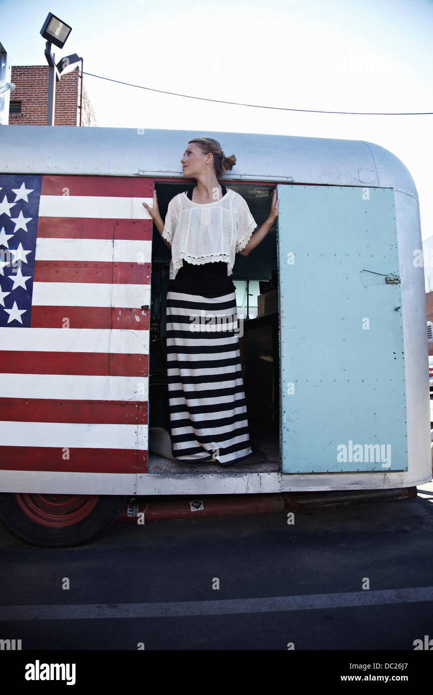 Donna in piedi nella porta della carovana con bandiera americana Foto Stock