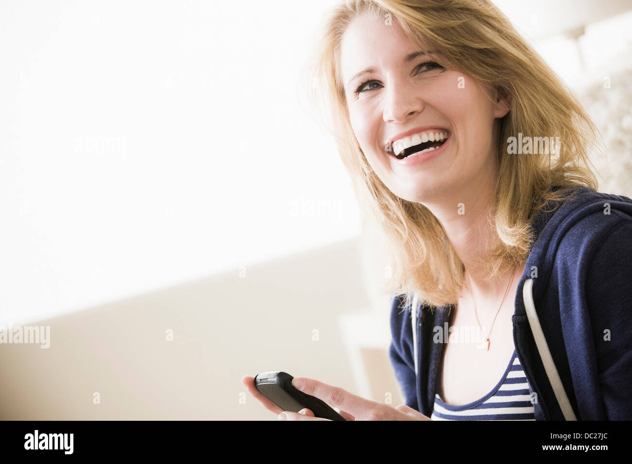 Giovane donna con un telefono cellulare, ridendo Foto Stock