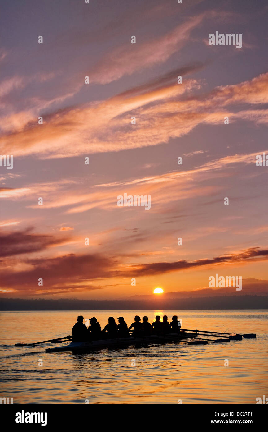 Otto persone di canottaggio al tramonto Foto Stock