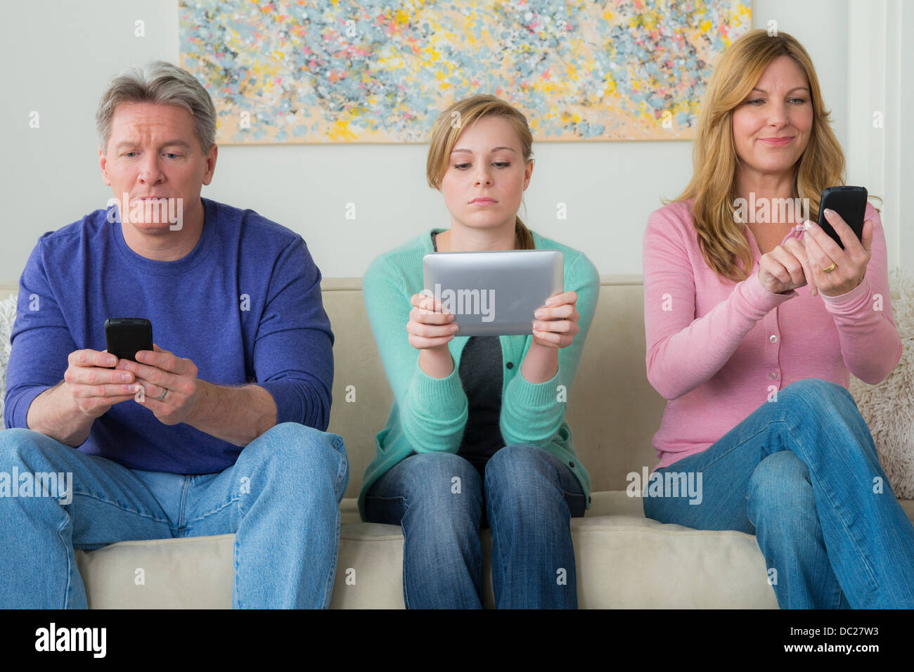 Famiglia con ragazza adolescente utilizzando dispositivi di comunicazione Foto Stock