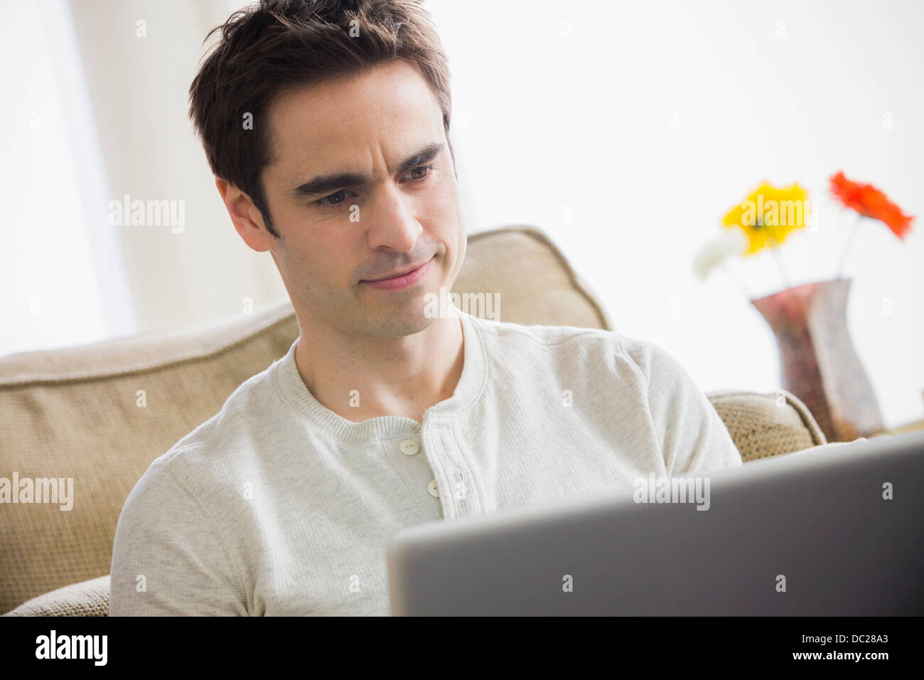 Metà uomo adulto utilizzando laptop, accigliata Foto Stock
